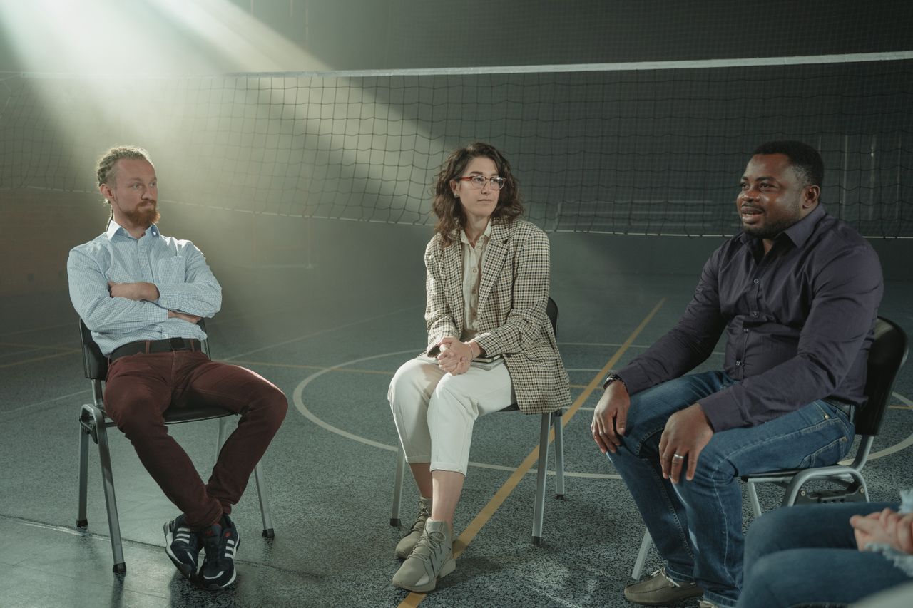 A multicultural group of people participating in a supportive therapy session indoors, fostering diversity and discussion.